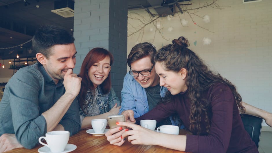 A group of young adults sharing a phone screen at a wood table inside an Austin cafe.